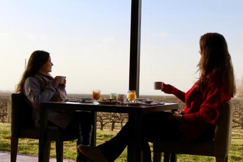 two women sitting at a table drinking coffee at Posada Salentein in Los Árboles
