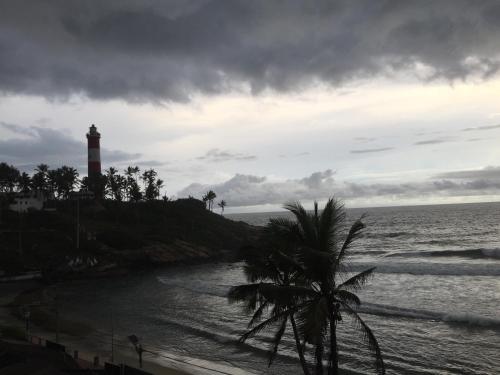 a lighthouse on a hill next to the ocean at The Ocean Park Beach Resort in Kovalam
