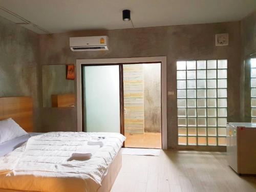 een slaapkamer met een groot bed en een glazen schuifdeur bij Sands Place Apartment and Hotel in Samut Sakhon