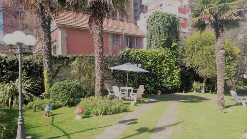 a garden with chairs and an umbrella and a building at Bologna Hotel Mar del Plata in Mar del Plata