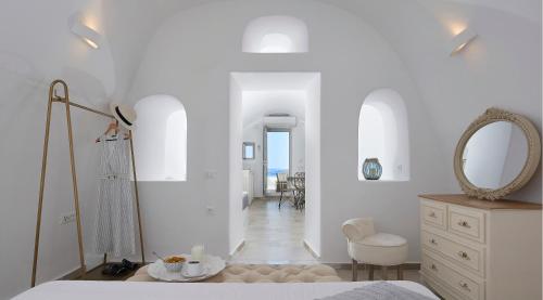 a white bedroom with a bed and a mirror at Amaya Selection of Villas in Oia