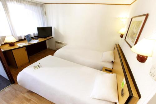 a hotel room with two beds and a desk at Campanile Villefranche-Sur-Saône in Villefranche-sur-Saône