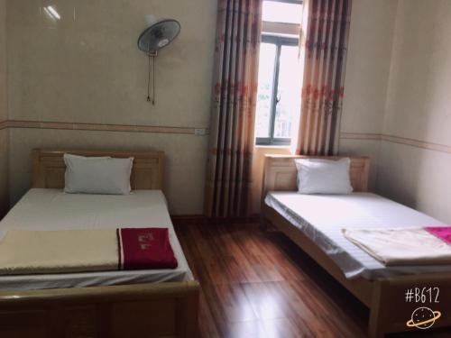 2 camas en una habitación pequeña con ventana en Thanh Binh Hotel, en Hà Tĩnh