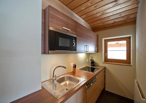 una pequeña cocina con fregadero y microondas en Apartment Bergsonne, en Samnaun
