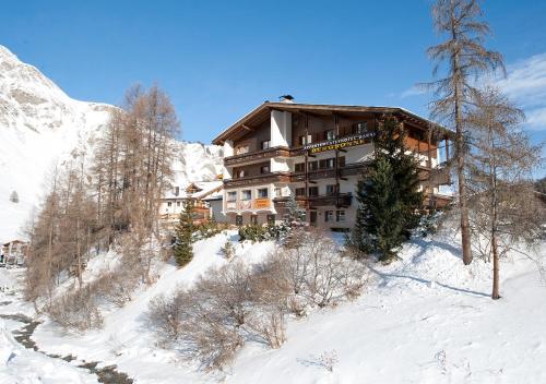 un edificio en una montaña cubierta de nieve con árboles en Apartment Bergsonne, en Samnaun