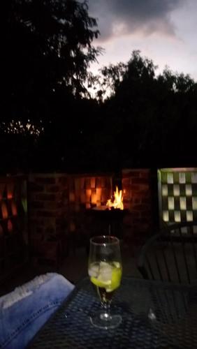 a glass of wine sitting on a table in front of a fireplace at Suikerbosrant Sleep and go in Pretoria
