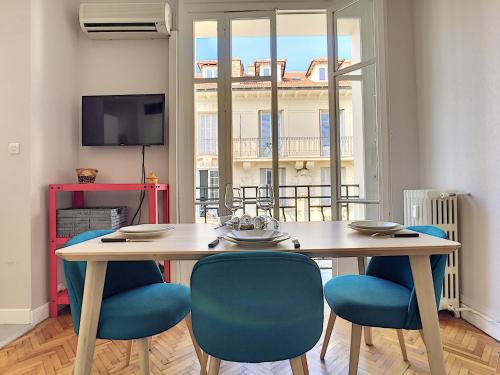 a wooden table with blue chairs in a living room at Nestor&Jeeves - LILAS BUFFA - Central - Close sea - Top Floor in Nice