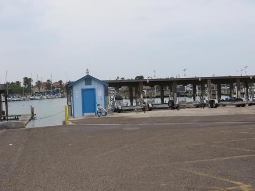 a blue building next to the water with a dock at White Sands Inn, Marina, Bar & Grill in Port Isabel