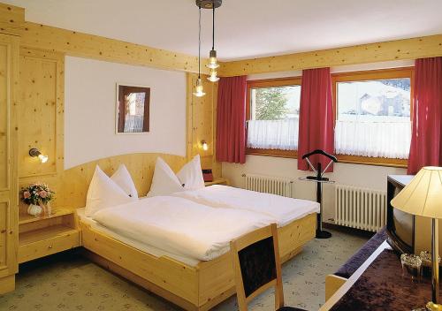 1 dormitorio con cama de madera en una habitación en Hotel Garni Bergsonne, en Samnaun