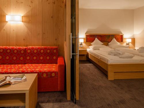a hotel room with two beds and a red couch at feldthurnerhof vinum-natur-relax in Feldthurns