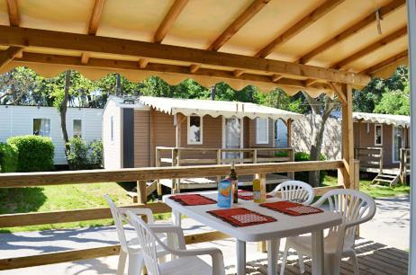 a table and chairs on a patio with a house at Camping Parc Mogador in Sanary-sur-Mer