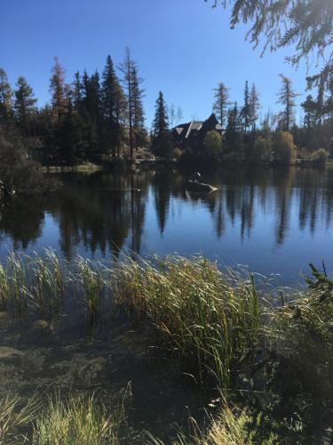 a view of a lake with a house in the background at Apartman Panorama 213, Štúdio Comfort in Štrbské Pleso