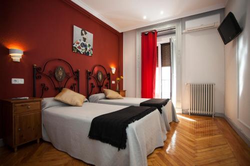 a bedroom with a bed and a red wall at Hostal Aresol in Madrid