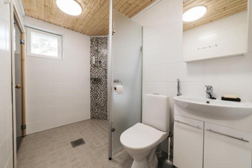 a white bathroom with a toilet and a sink at Jokiniemen Matkailu Cottages in Tölvä