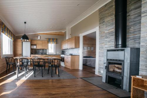 a kitchen with a fireplace and a table and chairs at Jokiniemen Matkailu Cottages in Tölvä