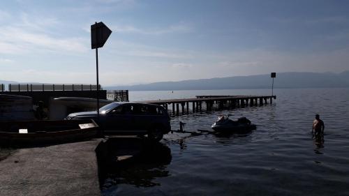 a car parked in the water next to a pier at Park Golden Beach Tasevski in Ohrid