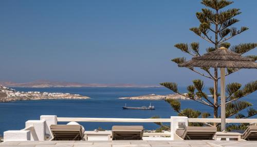 a group of chairs and a tree and the ocean at Hotel Alkyon in Mýkonos City
