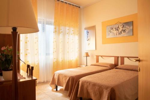 1 dormitorio con 2 camas, lámpara y ventana en Al Frantoio Maddii Levane bed and breakfast, en Levane