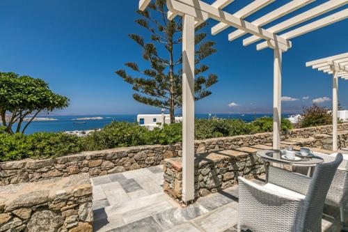 a patio with a table and chairs and a stone wall at Hotel Alkyon in Mýkonos City