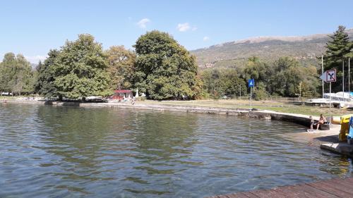 a large body of water with people sitting on the shore at Park Golden Beach Tasevski in Ohrid