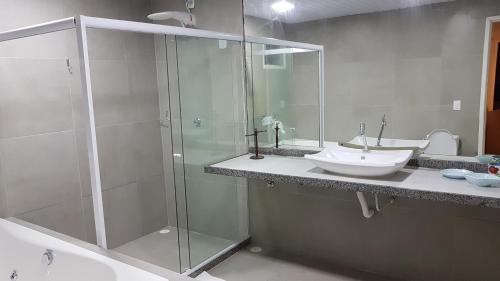 a bathroom with a glass shower and a sink at Pousada das Bromélias in Porto De Galinhas