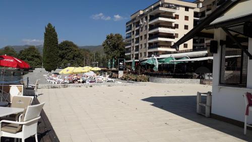 a patio with chairs and umbrellas next to a building at Park Golden Beach Tasevski in Ohrid