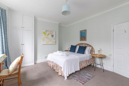 Dormitorio blanco con cama con almohadas azules en JOIVY Charming 3 bed house with a rooftop terrace, en Londres