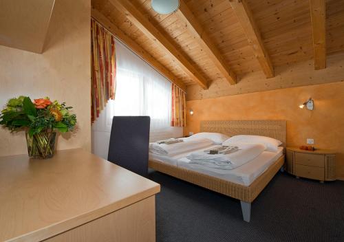 a bedroom with two beds and a table with a vase of flowers at Apart Primavera in Samnaun