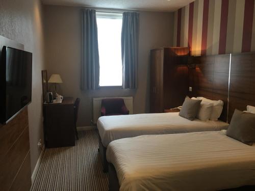 a hotel room with two beds and a television at The Victoria Hotel in Canterbury