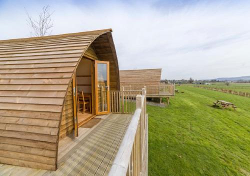 a small wooden cabin with a deck in a field at Mains Farm in Stirling