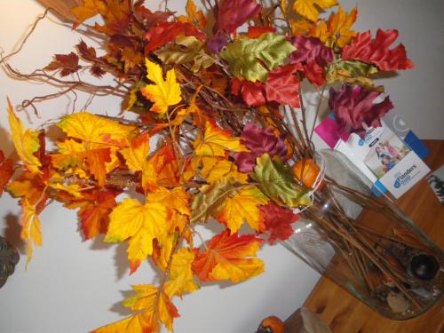 a vase filled with autumn leaves on a table at Hotel Amaryllis in Maldegem