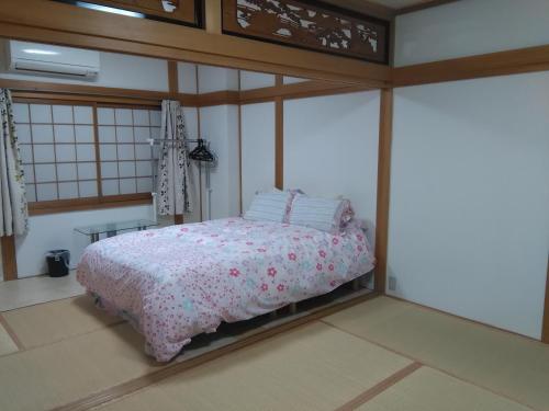 a bedroom with a bed with a pink comforter at Osaka Kuma House in Osaka
