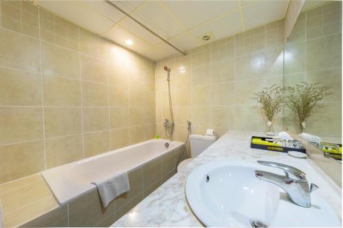 een badkamer met een wastafel en een bad bij La Dolce Vita Hotel in Hanoi