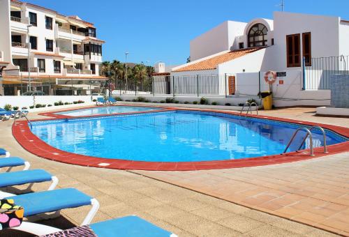 a large swimming pool with blue water in front of a building at FN FUNCHAL Tenerife 101 in El Guincho