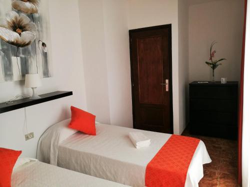 a bedroom with two beds with red pillows and a door at FN FUNCHAL Tenerife 101 in El Guincho