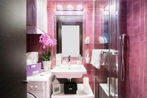 ローマにあるDiana Luxury Loftのピンクのタイル張りのバスルーム(シンク、鏡付)