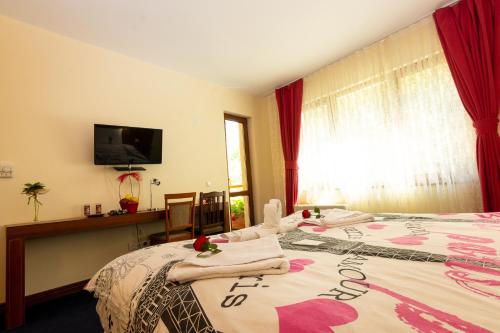 a hotel room with a bed with a flowered blanket at Hotel Saint Nedelya in Kolarovo