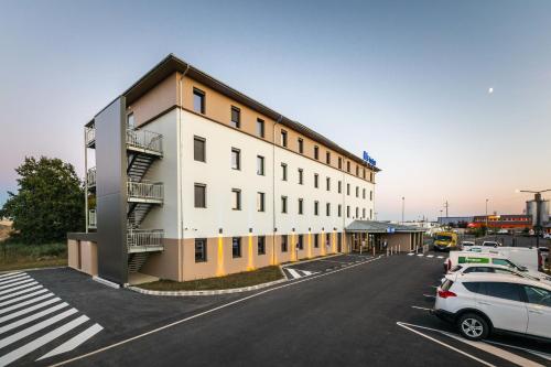 a large white building with cars parked in a parking lot at ibis budget Rennes Rte Lorient in Rennes