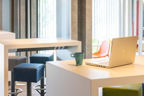 an office with a laptop on a desk with chairs at ibis budget Rennes Rte Lorient in Rennes