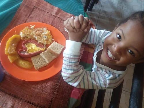 a young child sitting at a table with a plate of food at Nine Miles Cultural Hangouts and Tours in Stepney
