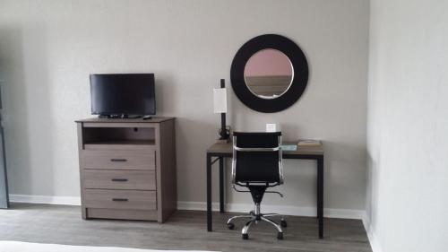 escritorio con silla, TV y espejo en Econo Lodge Inn & Suites, en Abilene