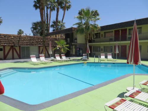 a swimming pool with a tennis court and a blue chair at Desert Lodge in Palm Springs