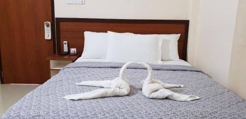 two pair of white shoes on a bed at Hulhan'gu Lodge in Himmafushi