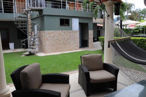 a hammock and chairs on a patio with a yard at 11B Jaco Sol Quadplex in Jacó