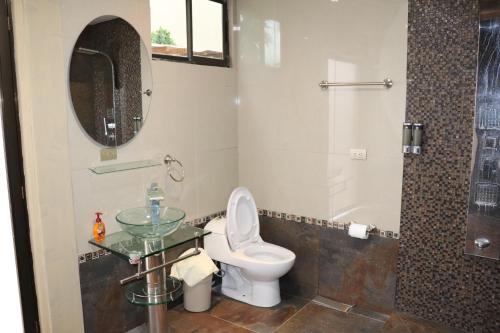 a bathroom with a toilet and a glass sink at 11B Jaco Sol Quadplex in Jacó