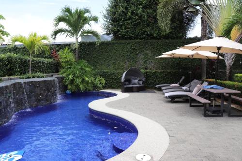 a swimming pool in a yard with chairs and an umbrella at 11B Jaco Sol Quadplex in Jacó