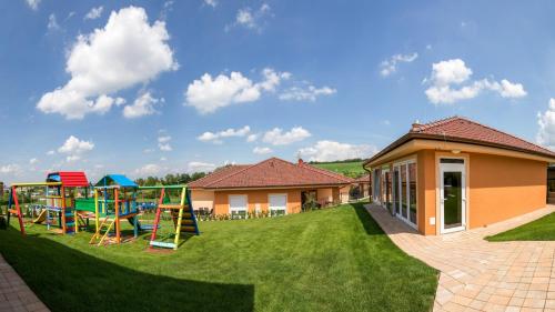 a yard with a playground in front of a house at Villa Gracia Podhájska in Podhájska