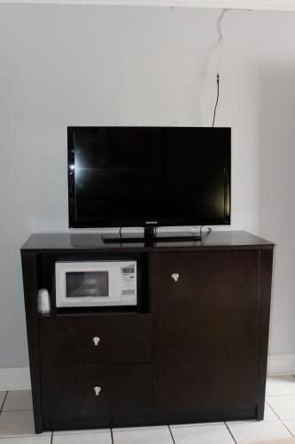 a black entertainment center with a tv and a microwave at Ramona Motel in Miami