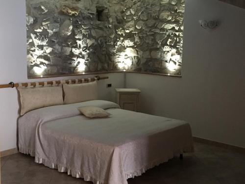 sypialnia z łóżkiem i kamienną ścianą w obiekcie Foresteria La Ceriola w mieście Monte Isola