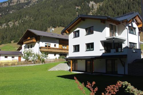 a large white building with a green yard at Apart Alpenjuwel in Sankt Leonhard im Pitztal